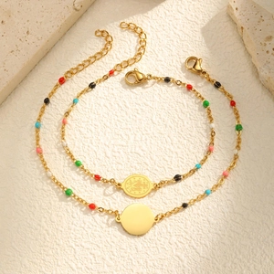 Detailed macro of two gold beaded bracelets with colorful enamel charms and religious medals