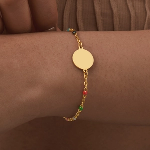 Close-up of gold stainless steel bracelet with colorful beads and engravable medal