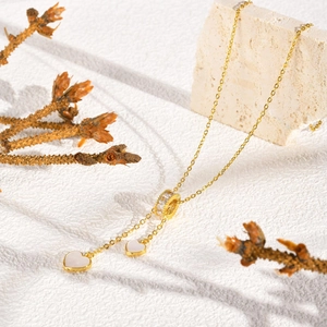 Détail du collier doré avec anneau en zircon et pendentifs cœur blanc sur pierre
