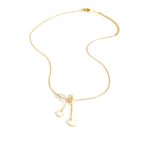 Détail d'un collier en titane doré avec fermoir en zircone et deux pendentifs en forme de cœur