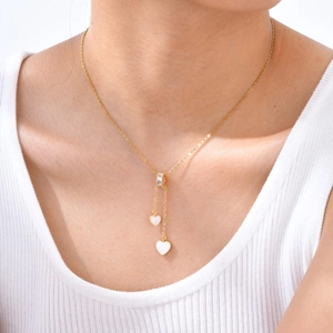 Détail d'un collier en Y doré avec pendentifs cœurs sur le cou d'un mannequin