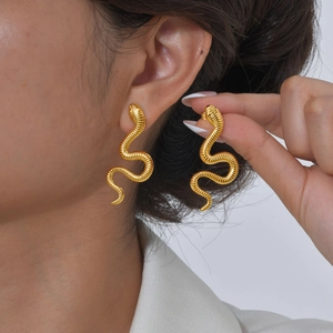 Close-up of gold-plated snake earrings with detailed scale texture on a female model
