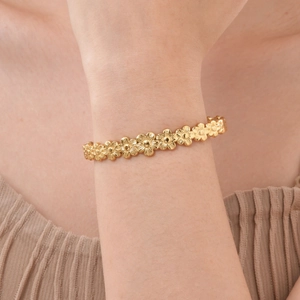 Detail shot of dainty 18K gold daisy flower chain bracelet on a model wrist
