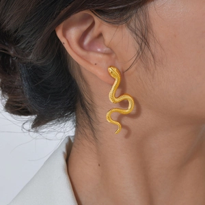 Detailed view of a gold snake earrings featuring scale textures on a female model