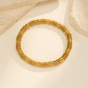Macro detail of golden stainless steel spring coil armlet with wavy texture design