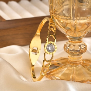 Close-up of golden stainless steel bracelet with Roman numerals and center zircon stone
