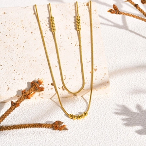 Détail d'un collier chaîne serpent dorée à plusieurs rangs avec perles polies sur pierre