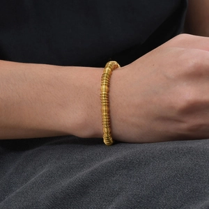 Close-up of golden stainless steel spring coil armband on wrist with textured metal detail