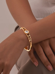 Detailed view of Roman numeral gold bangle with a large crystal on a model's wrist