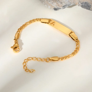 Macro shot of gold-plated curved ID bracelet with hollow letter A and lobster clasp