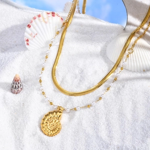 Vue macro d'un pendentif nautile en or 18 carats sur un collier double style plage