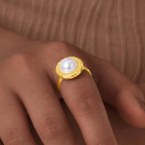Bague ouverte en acier doré 18K avec perle blanche ronde portée par un mannequin
