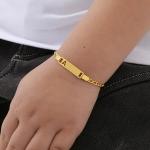 Detail of a child's gold-plated 18k bracelet with an openwork letter A on the curved plate