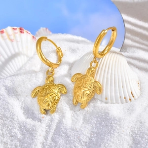 Détail de boucles d'oreilles tortue en or 18K avec textures coquillage sur sable