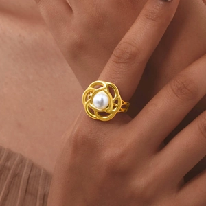 Dettaglio dell'anello in acciaio dorato 18K con perla bianca e motivo a fiori intrecciati