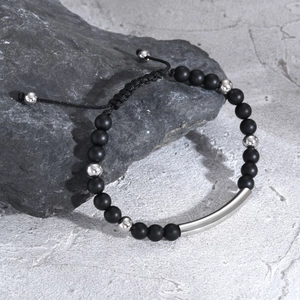 Macro detail of men's matte black agate beaded bracelet with polished silver curved metal tube