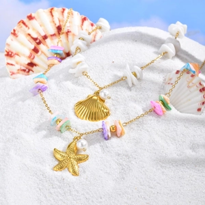 Golden sea shell and starfish pendant necklaces with colorful beads on white beach sand
