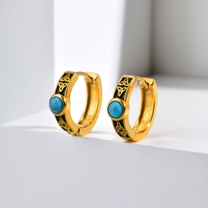 Macro view of Celtic knot enamel earrings with turquoise inlays on white cubes