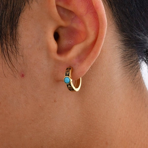 Macro shot of gold Celtic knot earring with green turquoise worn on a male ear