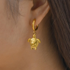 Gros plan sur une boucle d'oreille tortue en plaqué or 18 carats portée par un mannequin