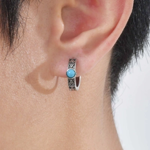 Detail of men's stainless steel Celtic knot earring with turquoise stone on ear