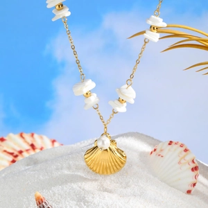 Macro detail of gold shell necklace with white pearls and shells on a beach background