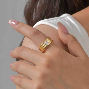 Polished gold multi-layer wide band ring with a rectangular zircon stone on a finger
