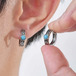 Close-up of vintage steel earring with Celtic knot patterns and a blue turquoise stone