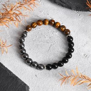 Detail of natural tiger eye and obsidian beaded bracelet on a stone surface