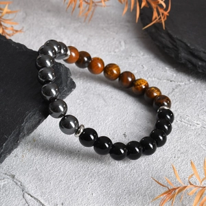 Detailed close-up of tiger eye and obsidian beaded bracelet on stone background