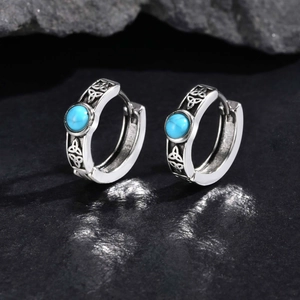 Detailed macro view of Celtic knot engravings on silver hoop earrings with blue stones