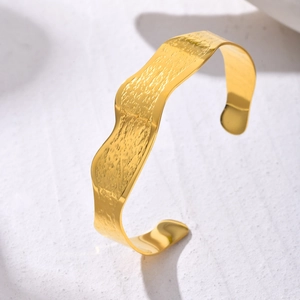 Macro detail of golden wave pattern stainless steel bracelet with hammered texture