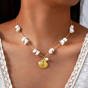 Close-up of a gold shell necklace with white pearls and small stones on a model