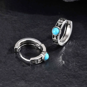Macro view of Celtic knot pattern and turquoise inlay on stainless steel hoop earrings