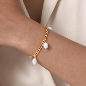 Dettaglio del bracciale a catena placcato oro 18K con perle barocche sul polso della modella