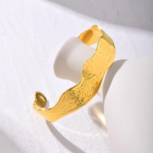 Detailed view of gold C-shaped wavy cuff bracelet with irregular hammered texture finish