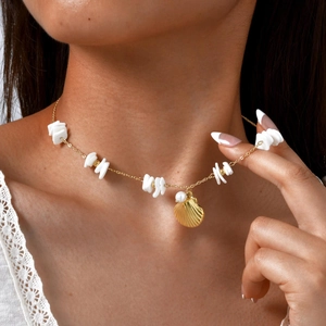 Detail of gold chain necklace with white shell chips, seashell pendant and pearl