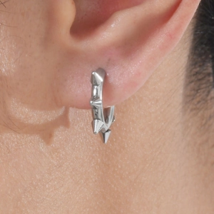 Nahaufnahme eines silbernen Edelstahl-Ohrrings mit Punk-Spikes an einem männlichen Ohr