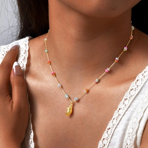 Detail of golden shell pendant necklace with colorful beads on female neck