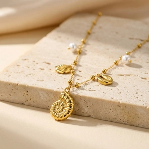 Collier nautique doré avec pendentif coquillage et perles blanches sur socle