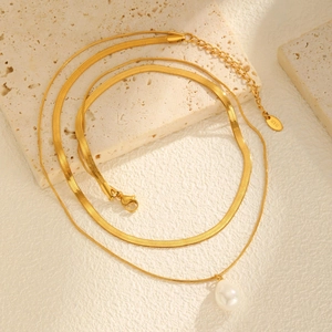 Detail view of double-layer gold snake chain with pearl pendant and K18 tag