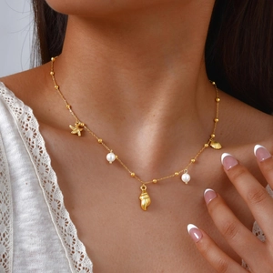 Détail du collier en acier inoxydable doré 18 carats avec coquillages et perle au cou