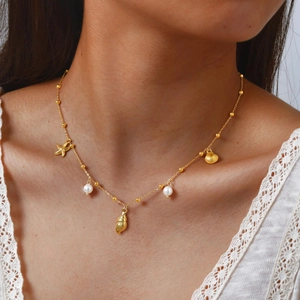 Collier doré en acier inoxydable avec breloques coquillage et perles sur un mannequin