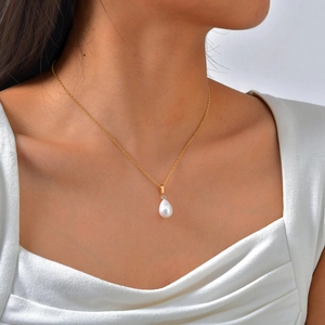 French vintage gold necklace with white teardrop pearl pendant and zircon on a model
