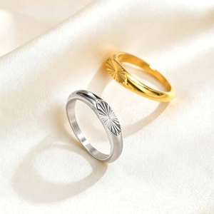 Detail of gold and silver men's oval rings with sunburst pattern on silk fabric