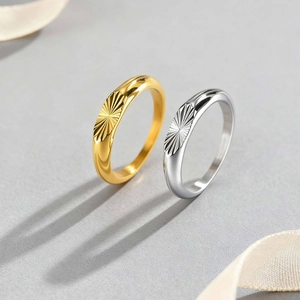 Close-up of gold and silver stainless steel rings featuring radial starburst engravings