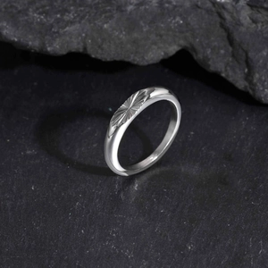 Macro view of silver oval ring with sunburst engraving on textured black stone