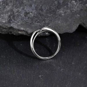 Macro shot of silver waved stainless steel ring with polished finish on gray rock