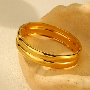 Detail view of double-layered 18K gold plated stainless steel hinged bangle on beige tray