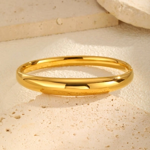 Detail of 18K gold-plated stainless steel bangle with polished finish and hinge closure